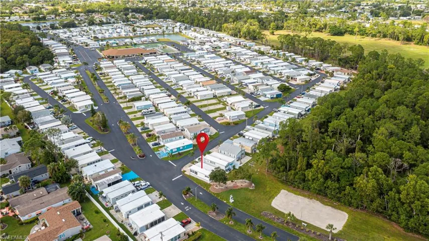 Aerial perspective of the residential site featuring a corner lot orientation, paved street access, and mature trees within the parcel boundaries