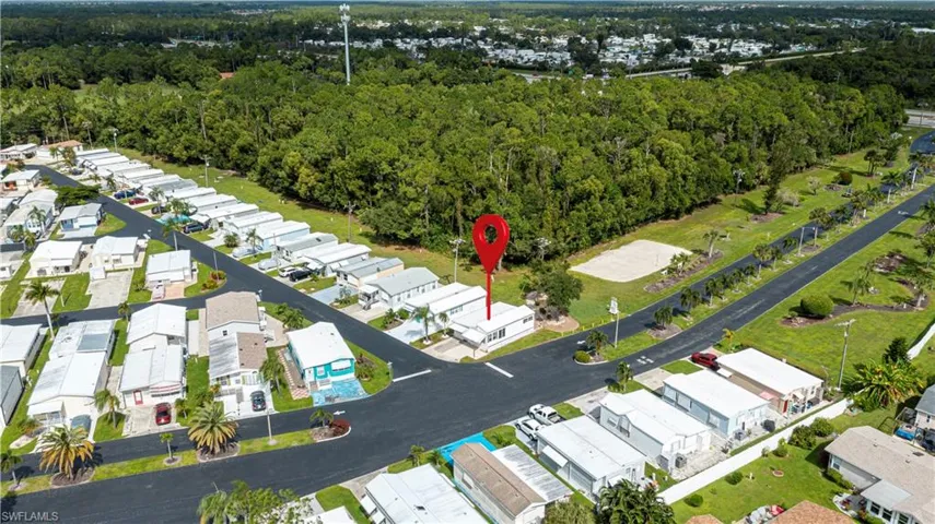 Aerial perspective of corner lot property featuring asphalt street frontage and perimeter access to dense, mature landscaping