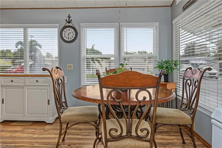 Wood-finish flooring, white built-in cabinetry with drawers, and multi-panel windows featuring adjustable blinds