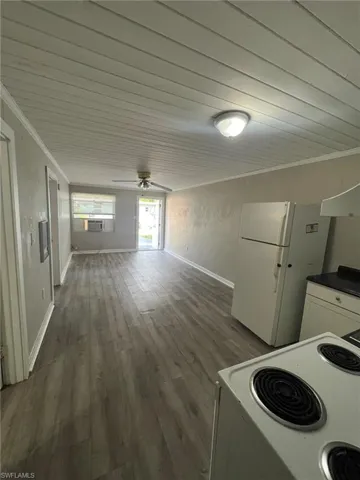 Kitchen with white appliances, dark wood-style flooring, crown molding, ceiling fan, and white cabinetry