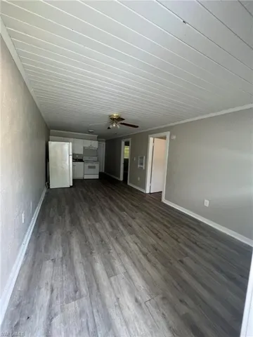 Unfurnished living room with a ceiling fan and dark wood-style flooring