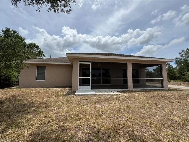 Back of property featuring stucco siding, a sunroom, and a yard