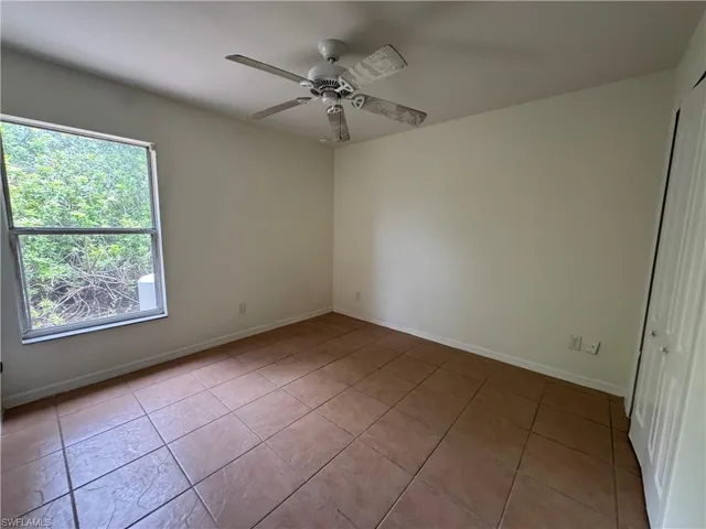 Spare room with tile patterned floors, ceiling fan, and baseboards