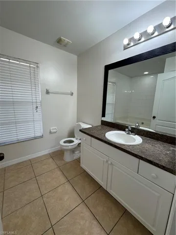 Bathroom with tile patterned flooring, vanity, toilet, and baseboards