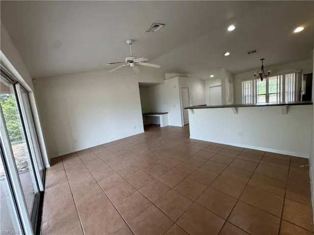 Spare room with a chandelier, light tile patterned flooring, vaulted ceiling, ceiling fan, and recessed lighting