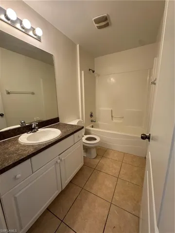Bathroom with tile patterned floors, vanity, bathtub / shower combination, and toilet