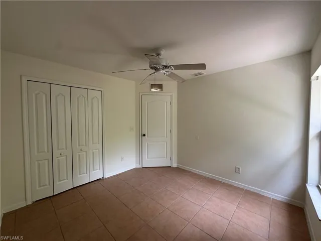 Unfurnished bedroom with tile patterned floors, a closet, a ceiling fan, and baseboards