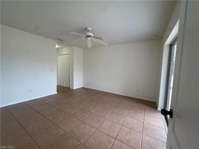 Empty room with light tile patterned floors, a ceiling fan, and baseboards