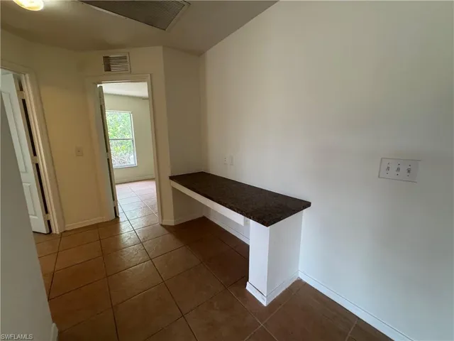Hallway with dark tile patterned flooring and baseboards