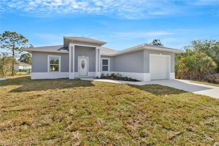 View of front facade featuring a garage and a front lawn