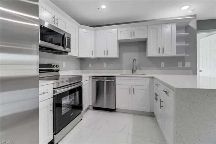 Kitchen with appliances with stainless steel finishes, sink, and white cabinets