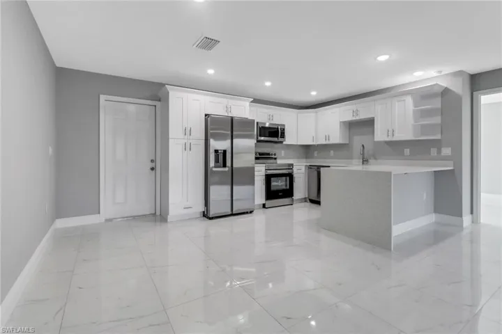 Kitchen featuring white cabinetry, stainless steel appliances, kitchen peninsula, and sink