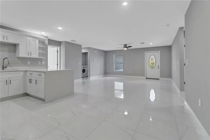 Kitchen featuring white cabinetry, washer / dryer, sink, and ceiling fan