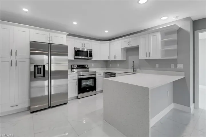 Kitchen featuring appliances with stainless steel finishes, sink, white cabinets, and kitchen peninsula