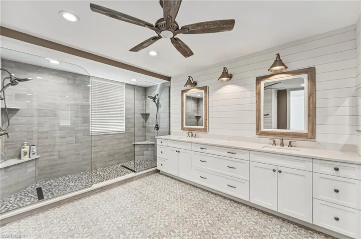 The oversized, reimagined shower evokes a true spa experience, complete with a seamless glass enclosure, floor-to-ceiling subway tile, dual shower heads, shiplap walls and beautifully appointed tile flooring underfoot—offering a daily sense of indulgent, resort-inspired relaxation.