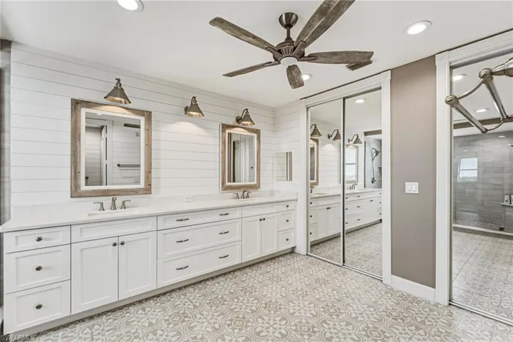 The primary bathroom evokes a true spa-like retreat, featuring dual vanities adorned with quartz countertops, a generous walk-in closet, and custom mirrors paired with designer lighting. Abundant drawers and thoughtfully designed storage complete the space with both elegance and functionality.