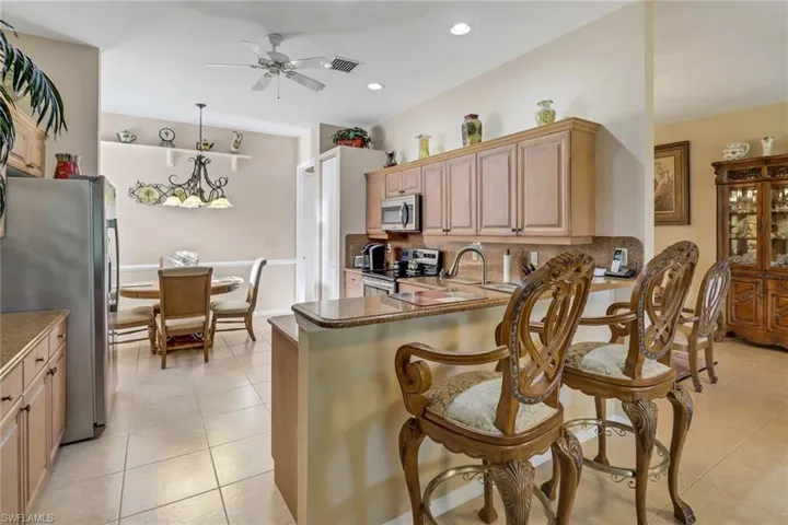 Kitchen featuring appliances with stainless steel finishes, kitchen peninsula, ceiling fan, and light tile patterned floors