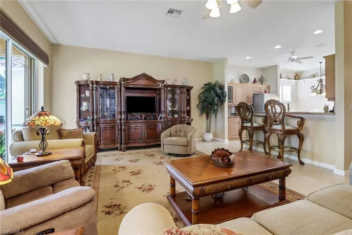 Living room featuring light tile patterned floors, a wealth of natural light, and ceiling fan