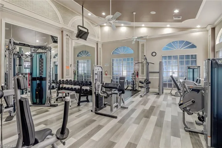 Exercise room with light hardwood / wood-style flooring, ceiling fan, and high vaulted ceiling