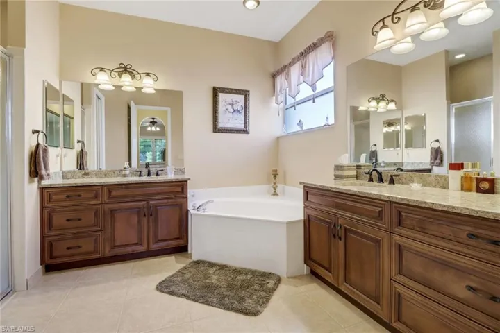 Bathroom with a tub to relax in, tile patterned floors, and double sink vanity