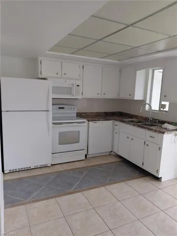 Kitchen featuring white appliances, white cabinetry, and decorative backsplash