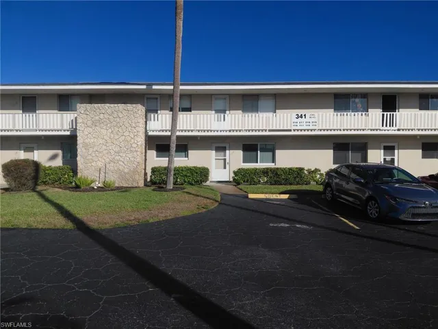 View of apartment building / complex featuring uncovered parking