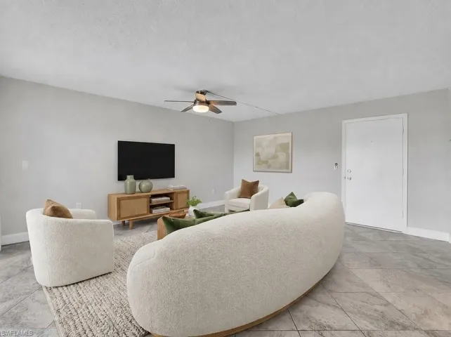 Virtual Staged Spacious living area featuring light gray walls, large format tile flooring, and a ceiling fan with integrated lighting