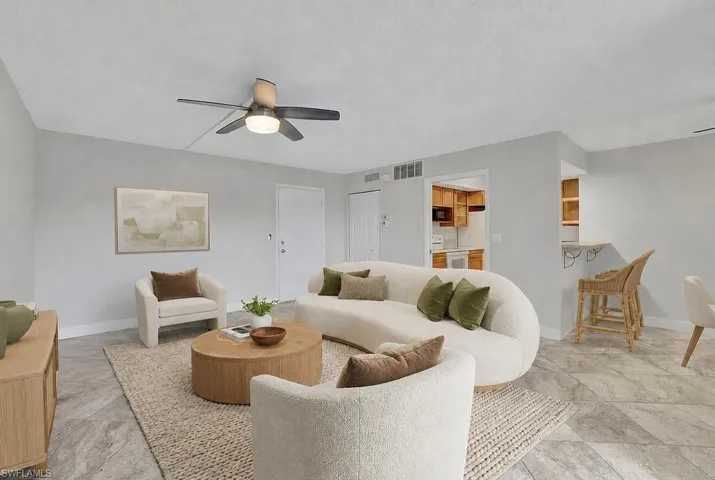 Virtual staged Spacious living area featuring light gray walls, a ceiling fan with integrated lighting, and durable tile flooring