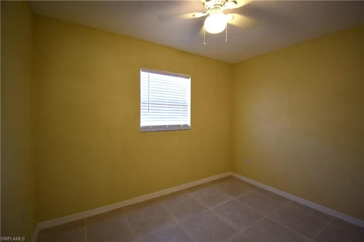 Room with tiled flooring, a single window with blinds, and a ceiling fan with integrated lighting