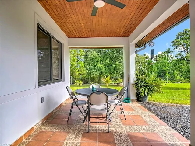 View of patio featuring outdoor dining space, ceiling fan, and view of scattered trees