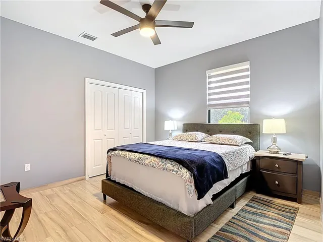 Bedroom with light wood-style floors, ceiling fan, and a closet