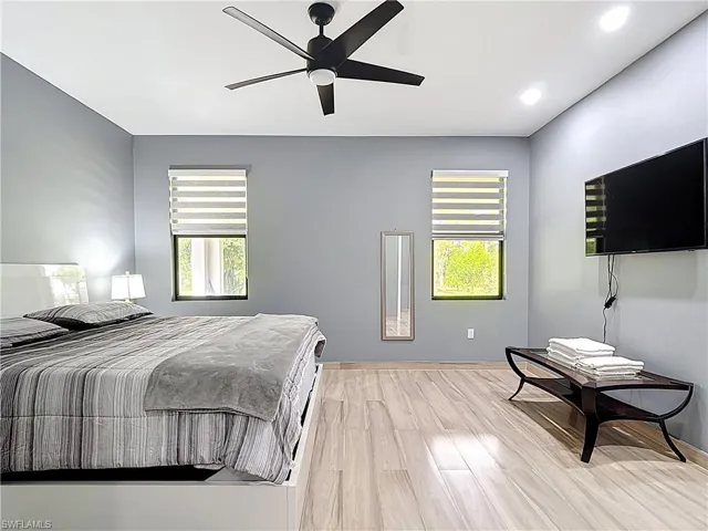 Bedroom with multiple windows, light wood-type flooring, a ceiling fan, and recessed lighting
