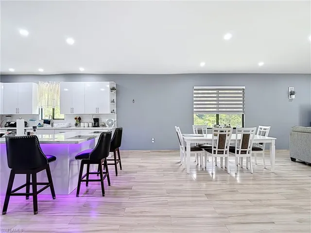 Kitchen featuring white cabinetry, a breakfast bar area, recessed lighting, open shelves, and tasteful backsplash