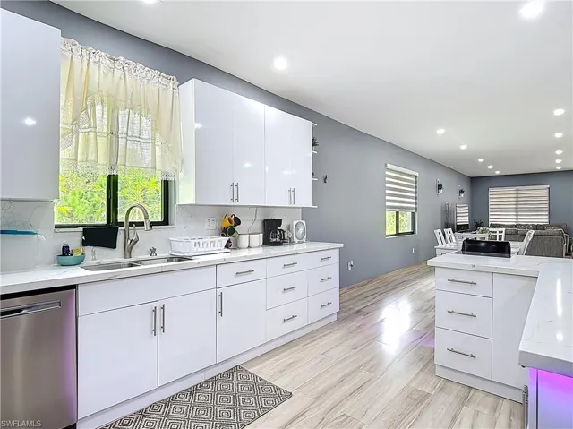 Kitchen with white cabinetry, dishwasher, recessed lighting, backsplash, and light wood-style floors