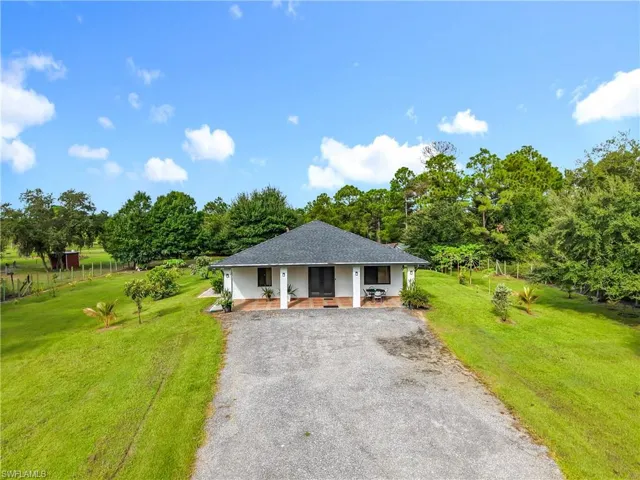 View of front of house with a front lawn, asphalt driveway, a porch, and a shingled roof