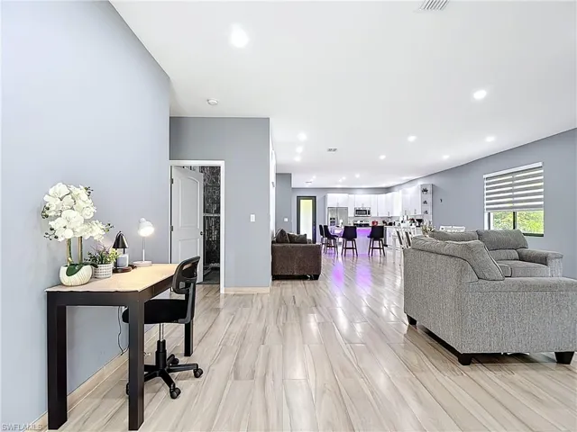 Living room with light wood finished floors, recessed lighting, and an office area
