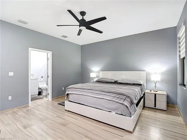 Bedroom featuring light wood finished floors, ceiling fan, and ensuite bath