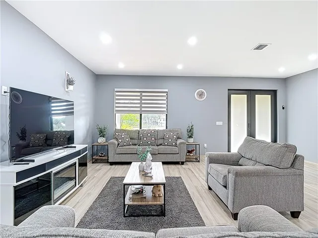 Living room with wood finished floors, recessed lighting, and french doors