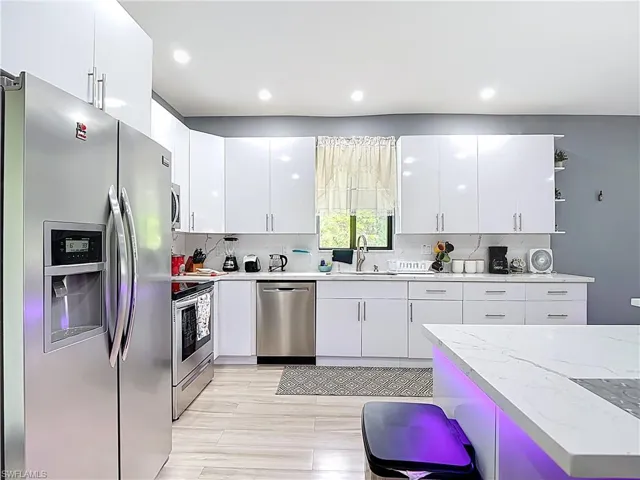 Kitchen featuring appliances with stainless steel finishes, open shelves, white cabinetry, backsplash, and recessed lighting