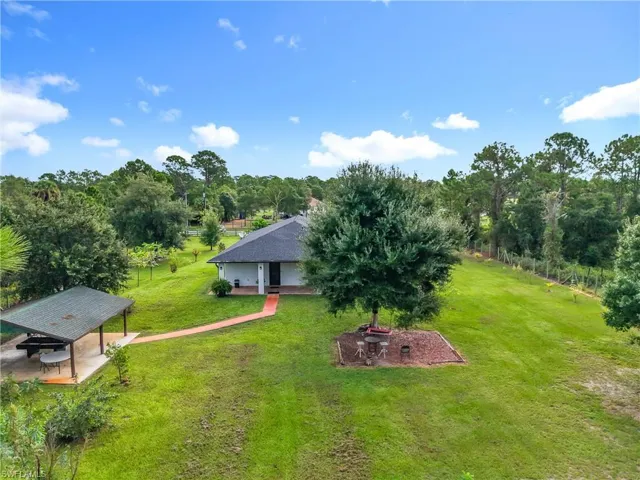 View of green lawn with a patio area and view of wooded area