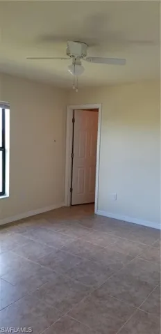 Spare room with ceiling fan and baseboards