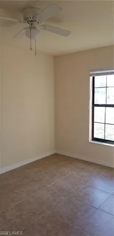 Empty room featuring ceiling fan and tile patterned floors