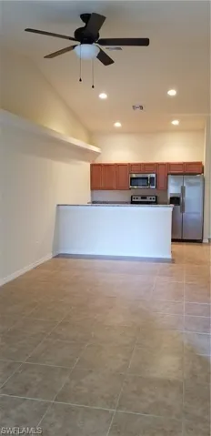 Unfurnished living room featuring a ceiling fan, lofted ceiling, recessed lighting, and light tile patterned flooring