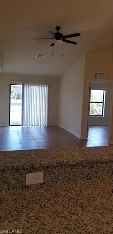 Unfurnished room featuring ceiling fan, light tile patterned floors, and vaulted ceiling