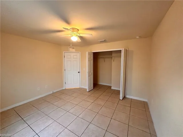 Unfurnished bedroom featuring a closet, ceiling fan, and light tile patterned floors