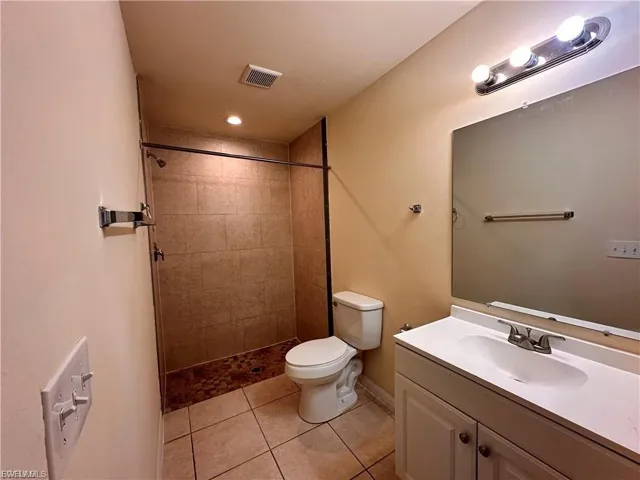 Bathroom featuring vanity, a shower stall, light tile patterned flooring, and recessed lighting