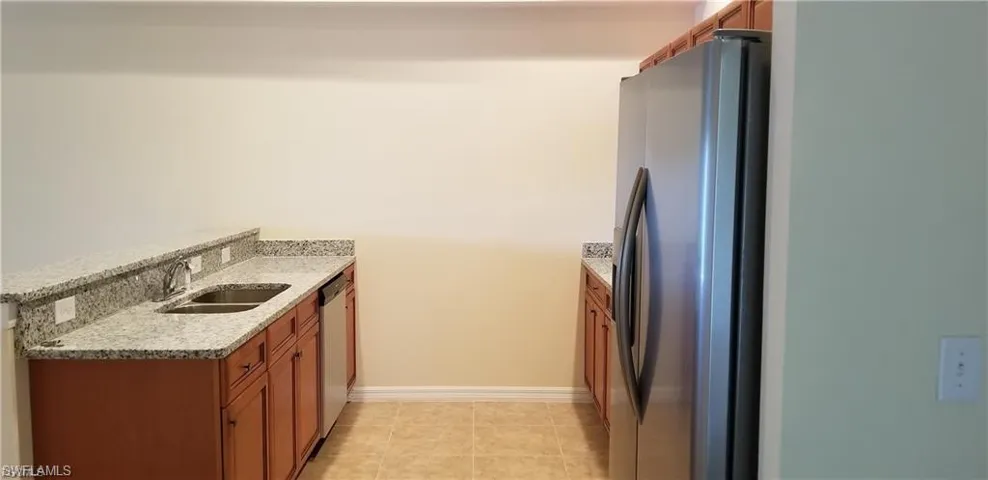 Kitchen featuring a peninsula, stainless steel appliances, light stone countertops, and wood finish cabinetry