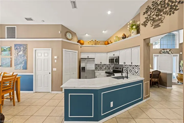 Kitchen featuring visible vents, a sink, stainless steel appliances, white cabinets, and light tile patterned floors
