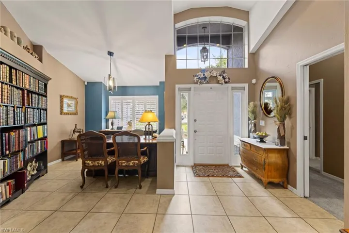 Foyer entrance with light tile patterned floors, baseboards, and lofted ceiling