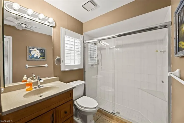 Bathroom featuring visible vents, a stall shower, toilet, and ceiling fan